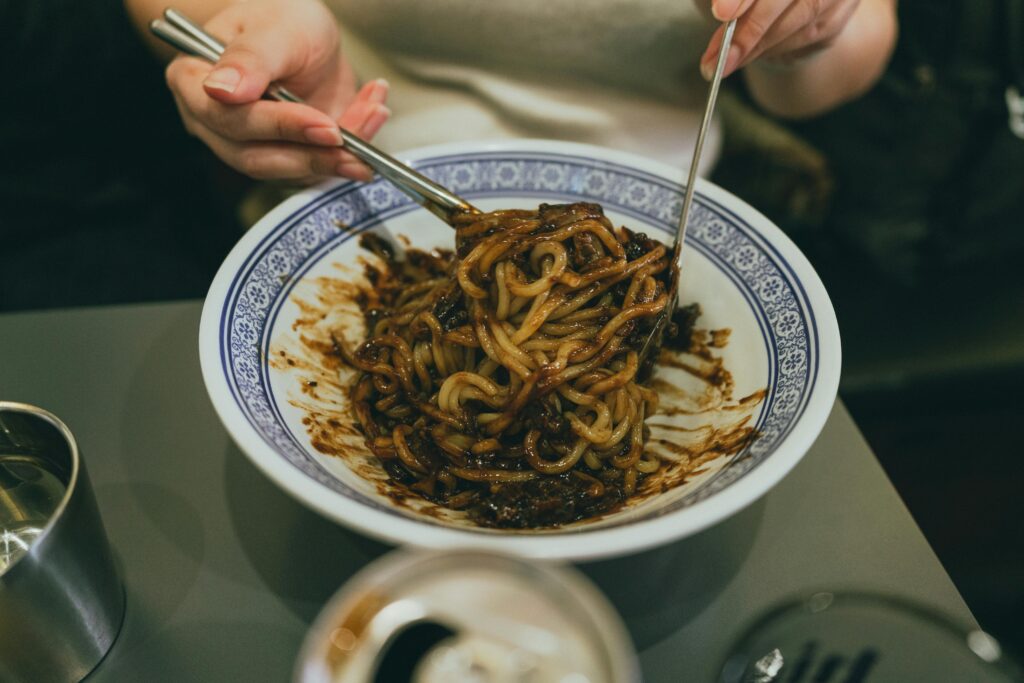 Close-up of a person enjoying traditional Korean jajangmyeon with chopsticks, highlighting Korean cuisine.