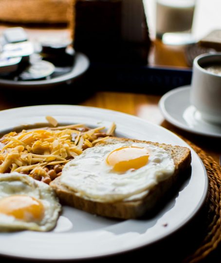 A hearty breakfast with fried eggs, baked beans, and toast served with coffee in a cozy setting.