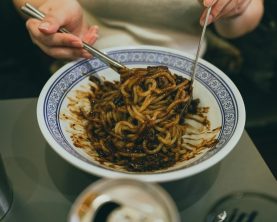 Close-up of a person enjoying traditional Korean jajangmyeon with chopsticks, highlighting Korean cuisine.