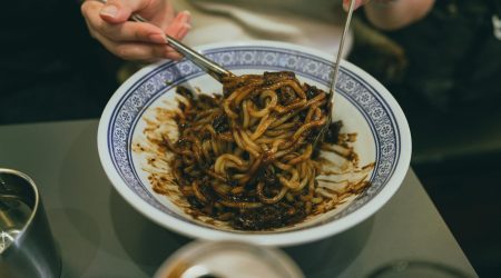 Close-up of a person enjoying traditional Korean jajangmyeon with chopsticks, highlighting Korean cuisine.