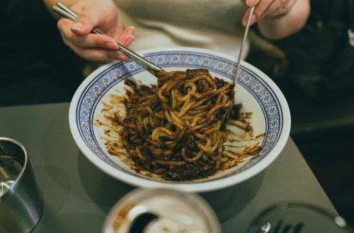 Close-up of a person enjoying traditional Korean jajangmyeon with chopsticks, highlighting Korean cuisine.