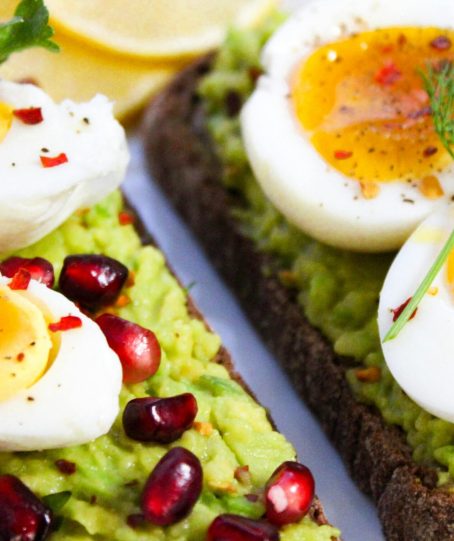 Savor this delicious avocado toast topped with soft-boiled eggs and garnished with pomegranate seeds.
