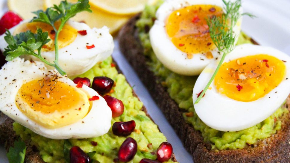 Savor this delicious avocado toast topped with soft-boiled eggs and garnished with pomegranate seeds.