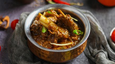 Close-up of a spicy mutton curry served in a traditional copper bowl, showcasing rich Indian flavors.
