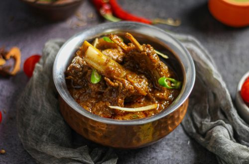 Close-up of a spicy mutton curry served in a traditional copper bowl, showcasing rich Indian flavors.