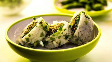 Close-up of sushi rolls garnished with green onions, served in a bowl.