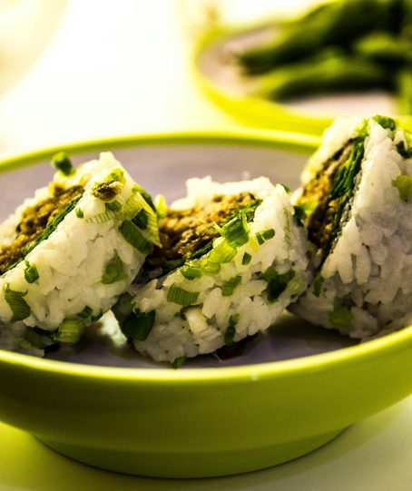 Close-up of sushi rolls garnished with green onions, served in a bowl.